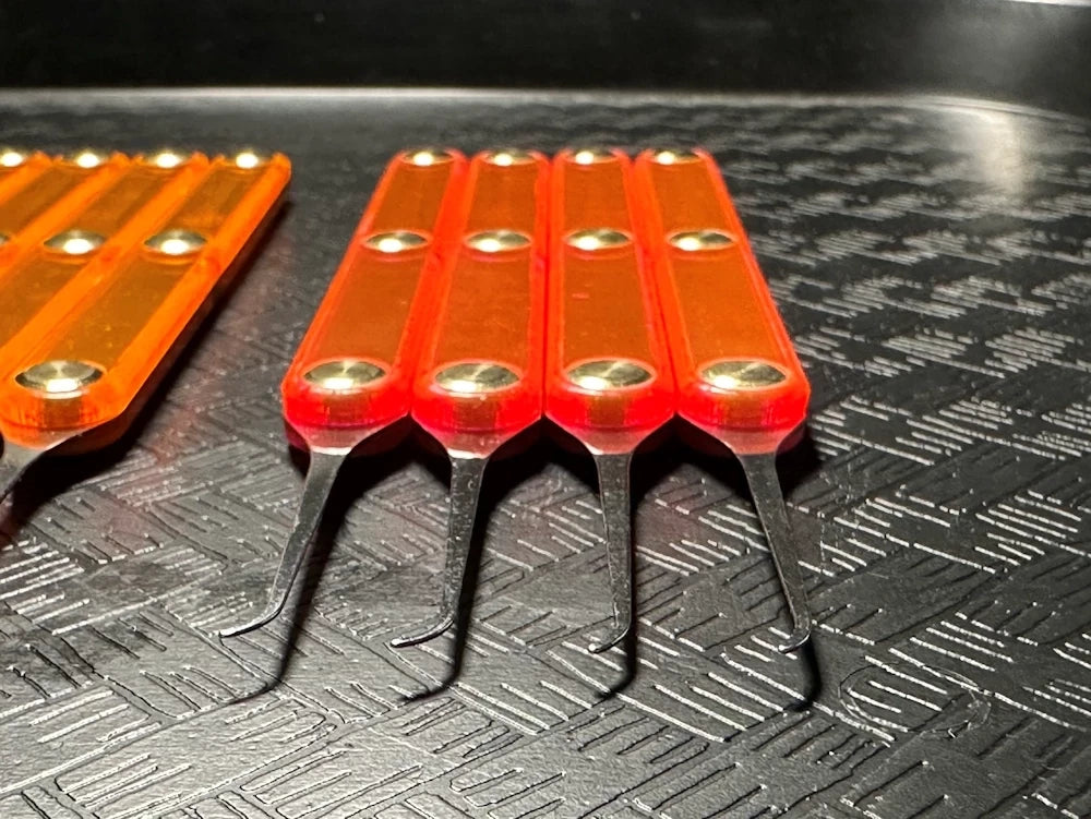 Set of orange tools with metallic tips on a textured black surface