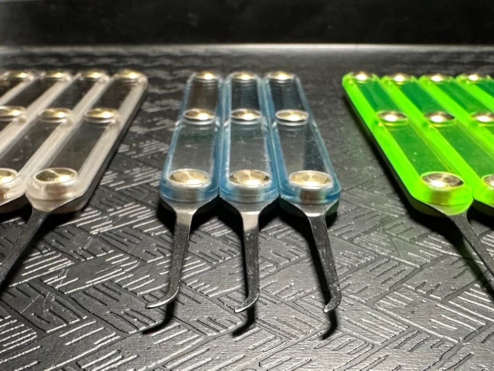 Set of metal tools with clear, blue and green handles on a textured surface