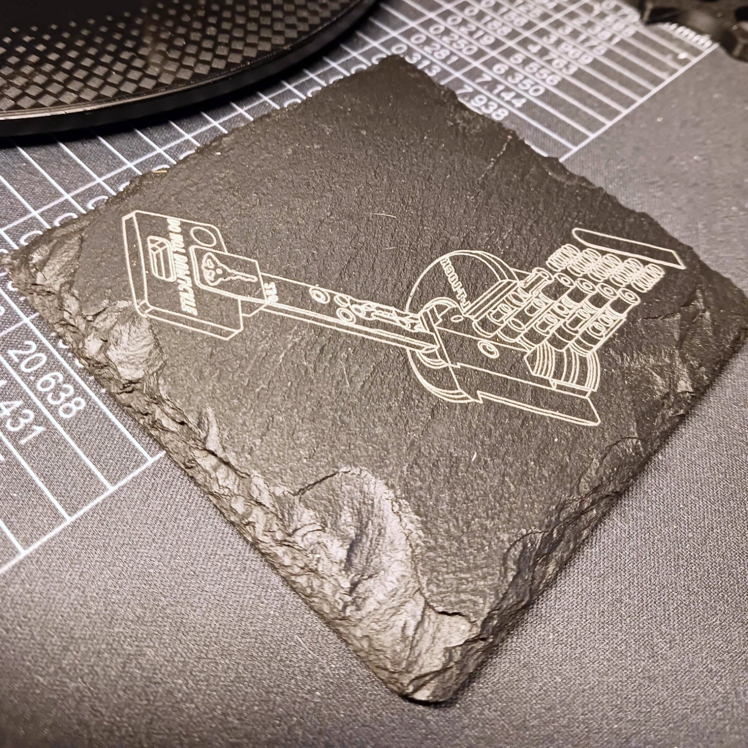 Slate coaster with laser-engraved design on a cutting mat