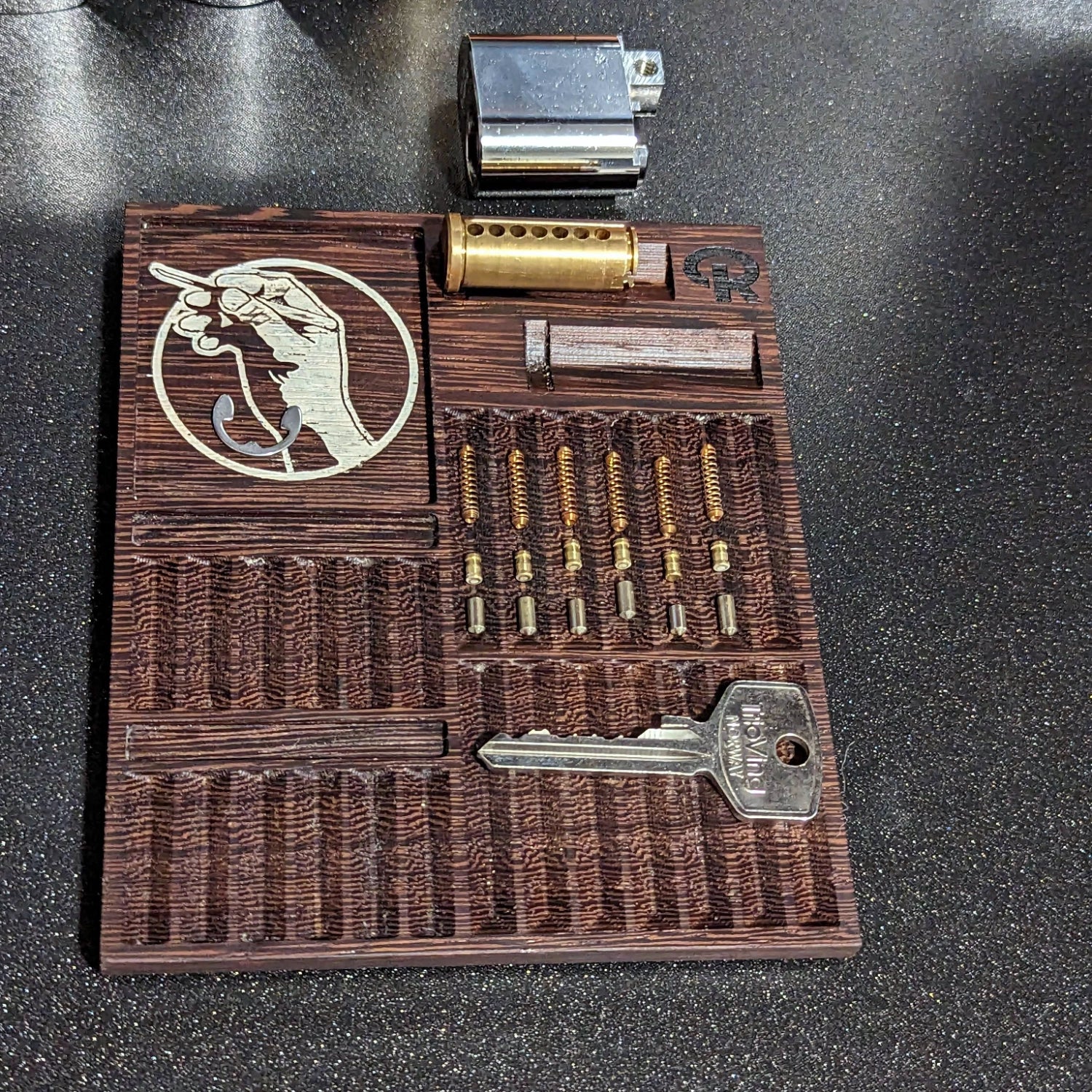 Wooden lock-picking tool set with various components on a dark surface