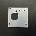 Clear square plastic block with circular hole on a black textured background